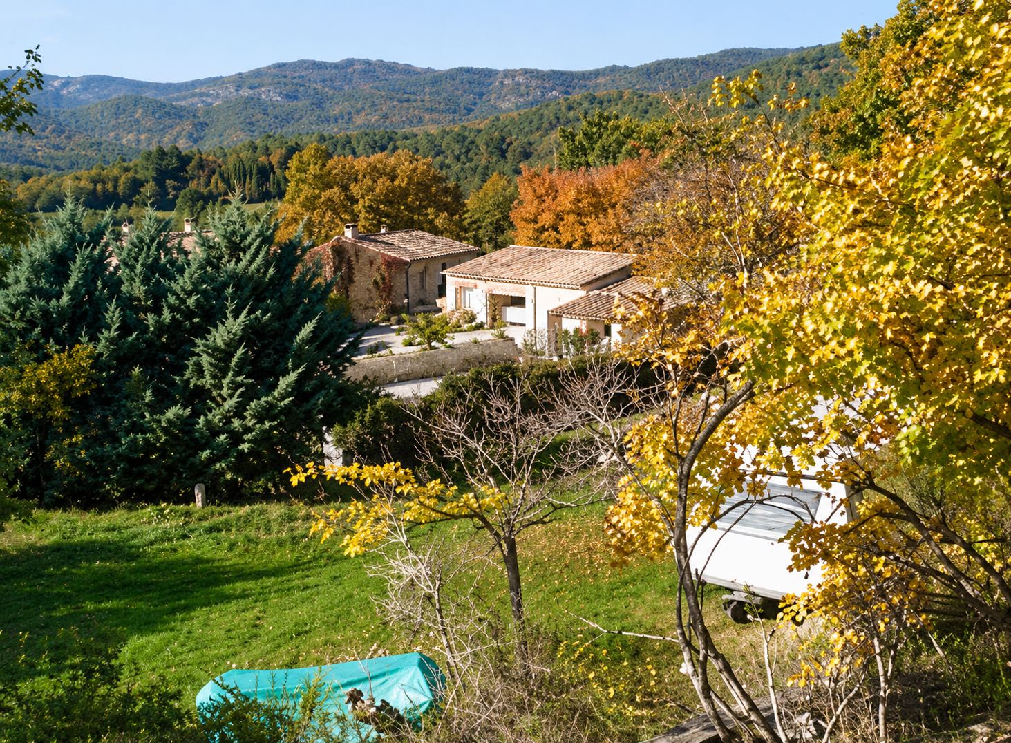 Le camping vu de haut : maisons de la ferme, pins, pelouse et arbres aux feuilles d’automne.