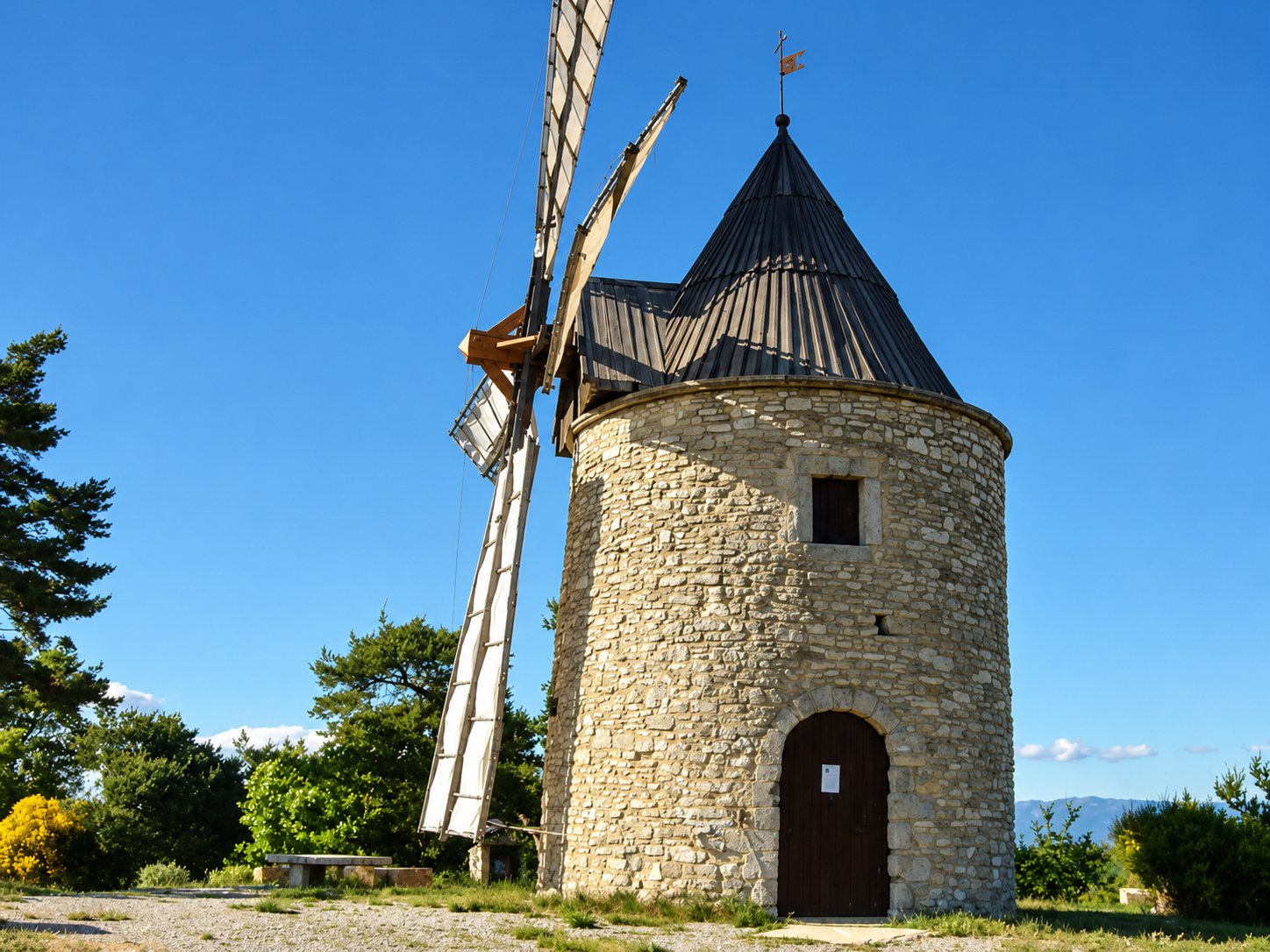 Le moulin à vent de Montfuron, tour en pierre à toit conique et ailes de toile.