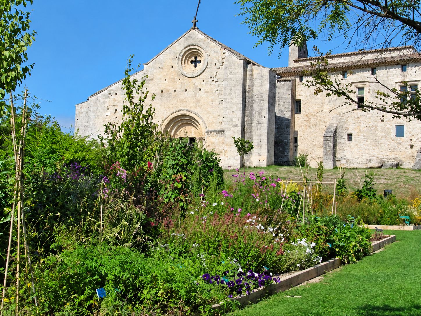 Jardin fleuri devant l’église et les bâtiments du prieuré de Salagon.